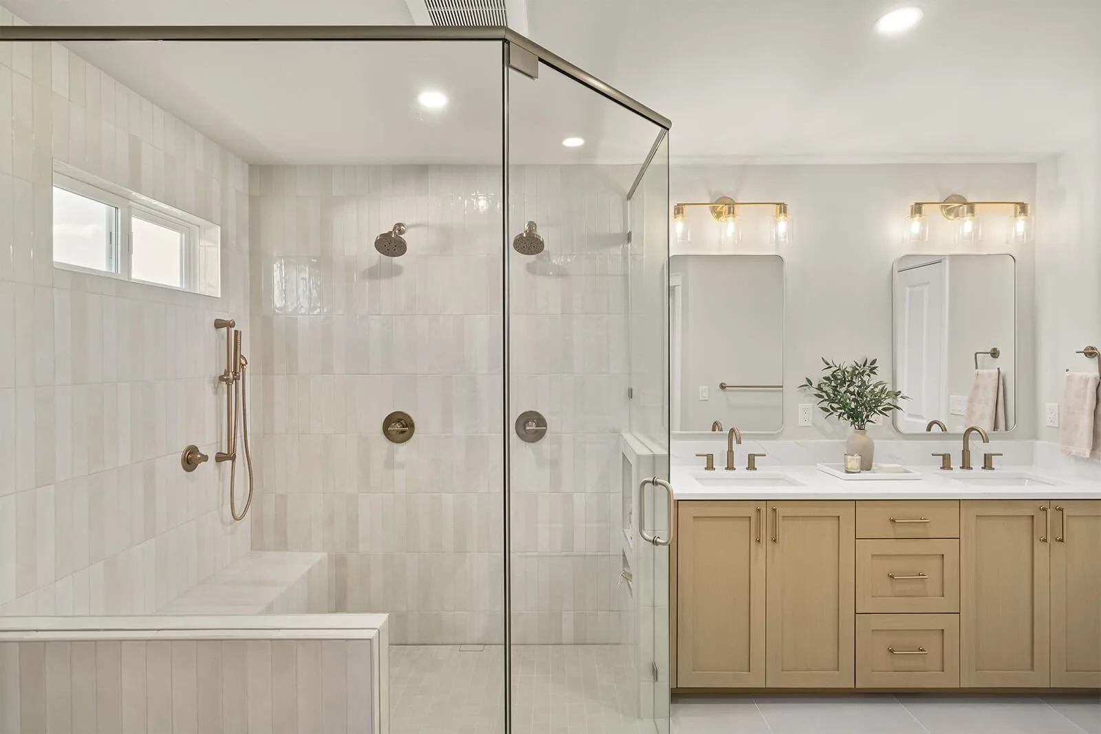 Finished bathroom with a glass walk-in tile shower, a built-in bench and window, and a double wood vanity
